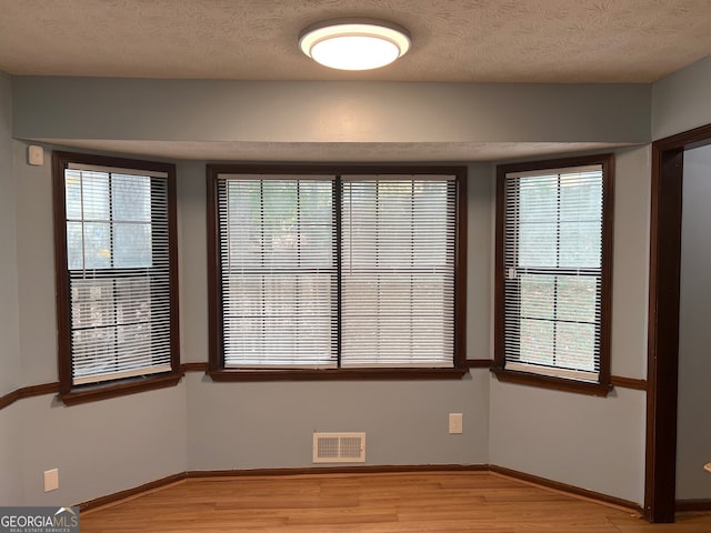 spare room with light wood-style floors, visible vents, and baseboards