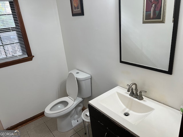 half bathroom with toilet, tile patterned flooring, baseboards, and vanity