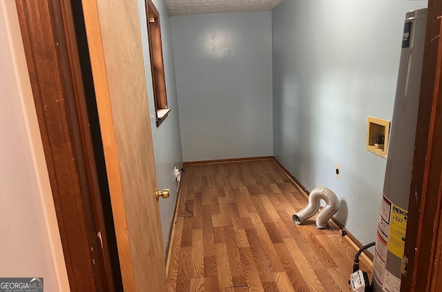 corridor with a textured ceiling, light wood finished floors, gas water heater, and baseboards