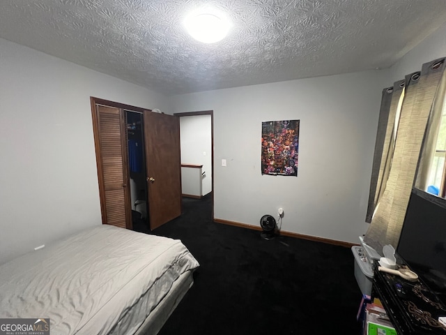 bedroom with baseboards, a closet, dark carpet, and a textured ceiling