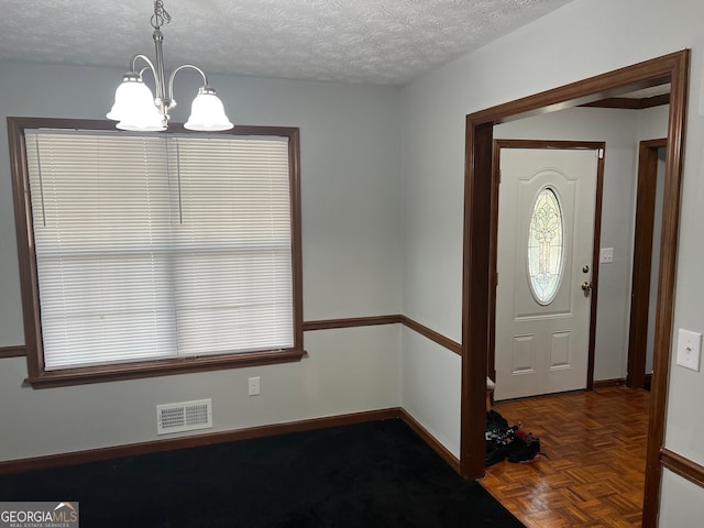 foyer featuring baseboards, visible vents, a chandelier, and a textured ceiling