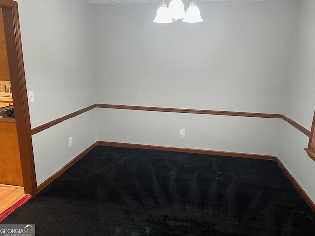 empty room featuring baseboards, carpet flooring, and a notable chandelier