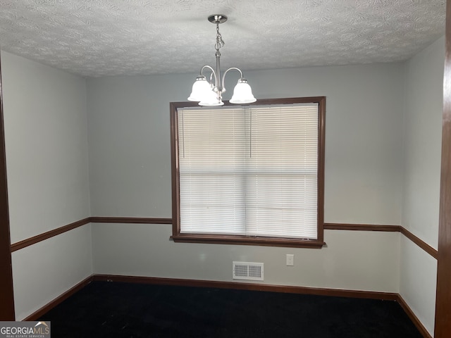 unfurnished dining area with a chandelier, a textured ceiling, visible vents, and baseboards