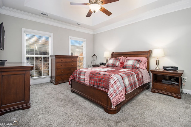 carpeted bedroom with crown molding, ceiling fan, and a raised ceiling