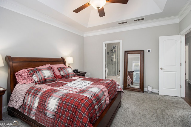 bedroom featuring crown molding, ensuite bath, carpet flooring, a tray ceiling, and ceiling fan