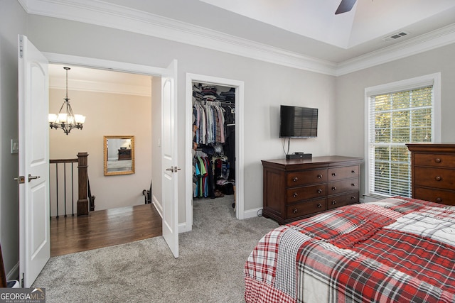 carpeted bedroom featuring crown molding, a walk in closet, a chandelier, and a closet