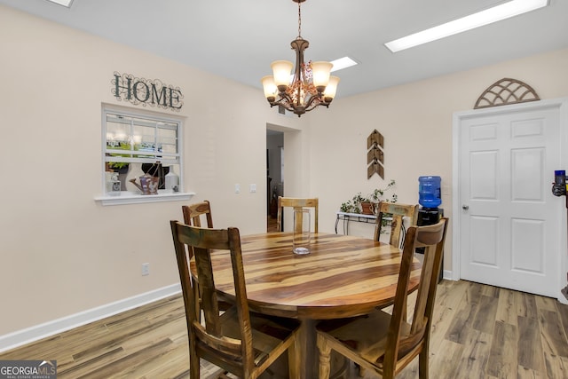 dining space with wood-type flooring and a notable chandelier