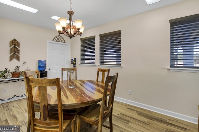 dining room with light wood-style floors, baseboards, and a chandelier