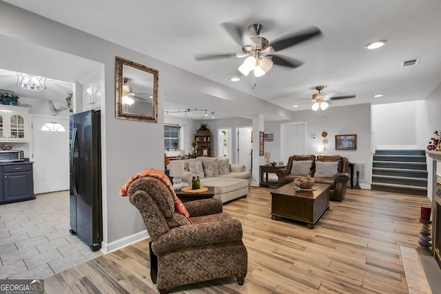 living area featuring visible vents, stairway, light wood-style flooring, and baseboards