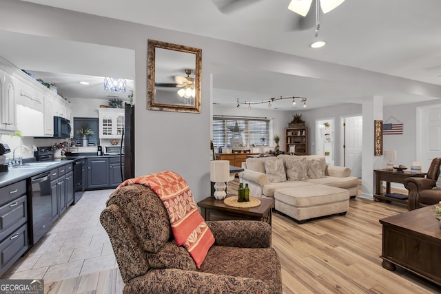 living room featuring light hardwood / wood-style floors, ceiling fan, and sink