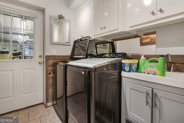 clothes washing area featuring washing machine and clothes dryer and cabinets