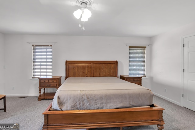 carpeted bedroom featuring visible vents, multiple windows, and baseboards