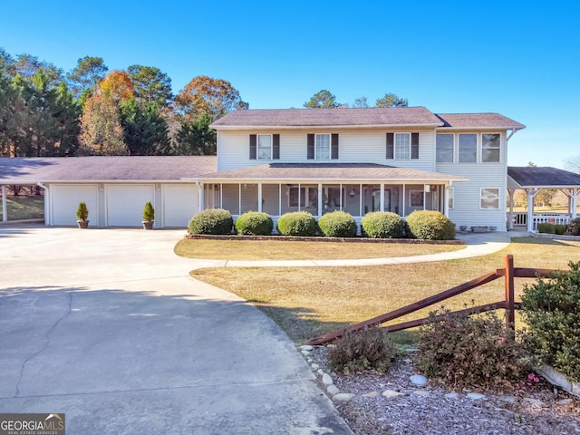 view of front facade featuring covered porch, a front yard, and a garage