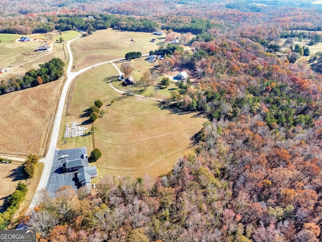 drone / aerial view featuring a view of trees and a rural view