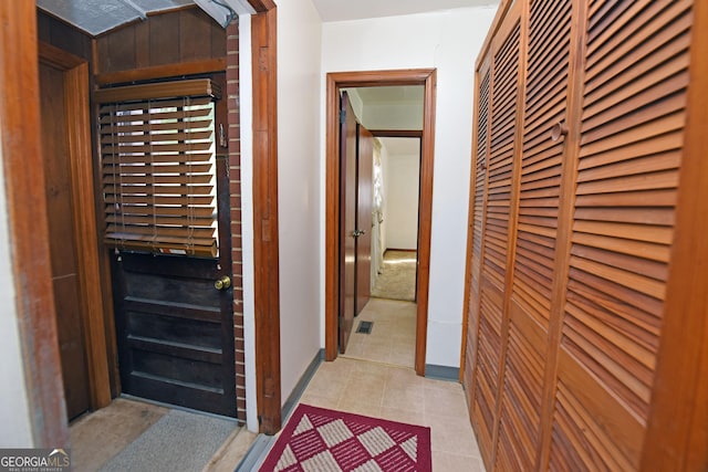 hallway with wood walls and light tile patterned floors