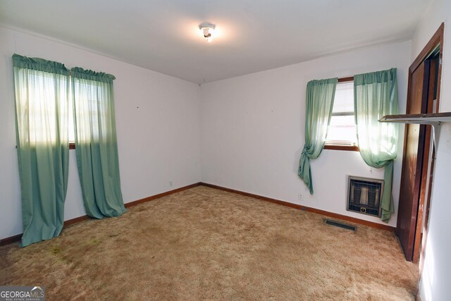 carpeted spare room featuring heating unit and a fireplace