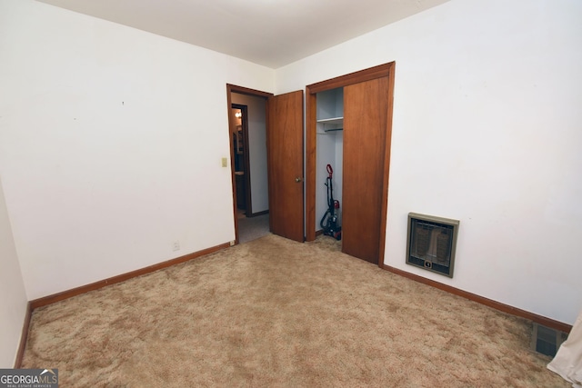 unfurnished bedroom featuring heating unit, a closet, and light colored carpet