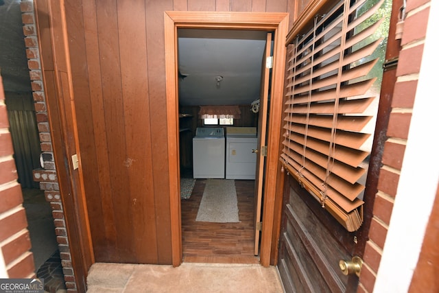 corridor featuring wood walls and washing machine and dryer