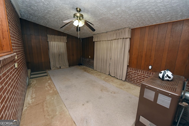 basement featuring wooden walls, light colored carpet, and a textured ceiling