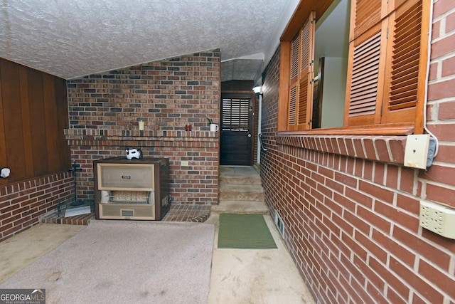 exterior space featuring brick wall, wood walls, a textured ceiling, lofted ceiling, and carpet