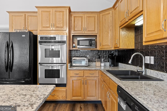 kitchen with light stone countertops, sink, stainless steel appliances, tasteful backsplash, and dark hardwood / wood-style floors