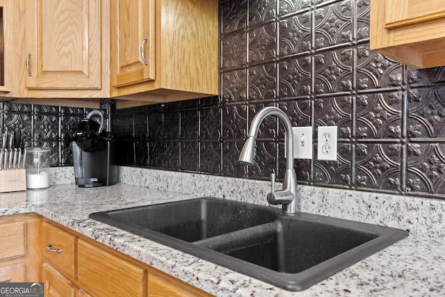 kitchen featuring decorative backsplash, sink, and light stone counters