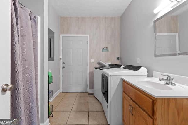 laundry area with sink, a textured ceiling, washing machine and dryer, and light tile patterned flooring