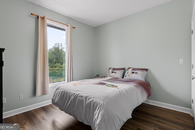 bedroom with a textured ceiling and dark hardwood / wood-style flooring