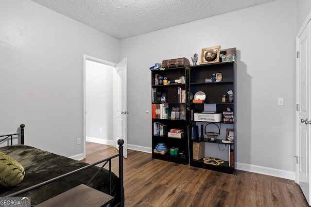 bedroom with a textured ceiling and dark hardwood / wood-style flooring