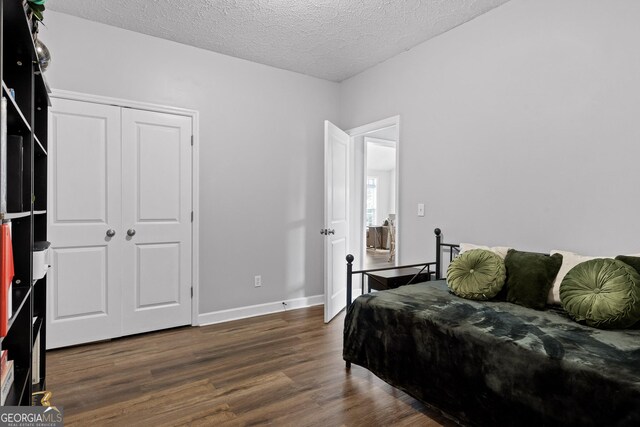 bedroom with a textured ceiling, dark hardwood / wood-style floors, and a closet