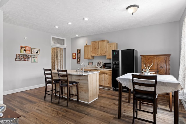 kitchen featuring sink, dark hardwood / wood-style flooring, black fridge with ice dispenser, and a kitchen island with sink