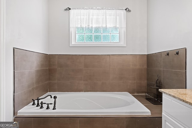 bathroom featuring tiled bath and vanity