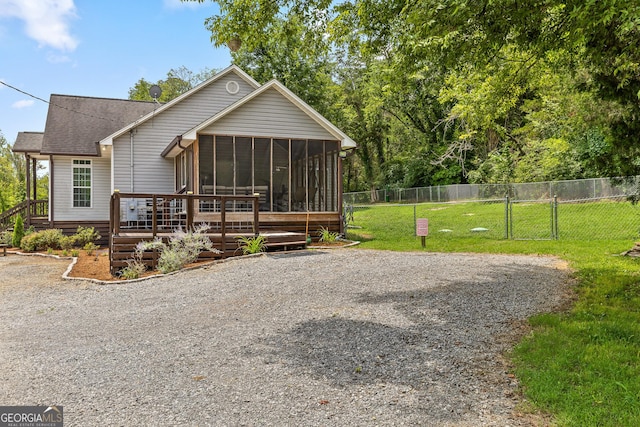 view of front of property with a sunroom, a deck, and a front yard