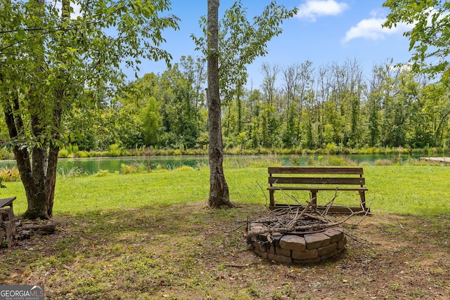 view of property's community featuring a water view, a fire pit, and a lawn