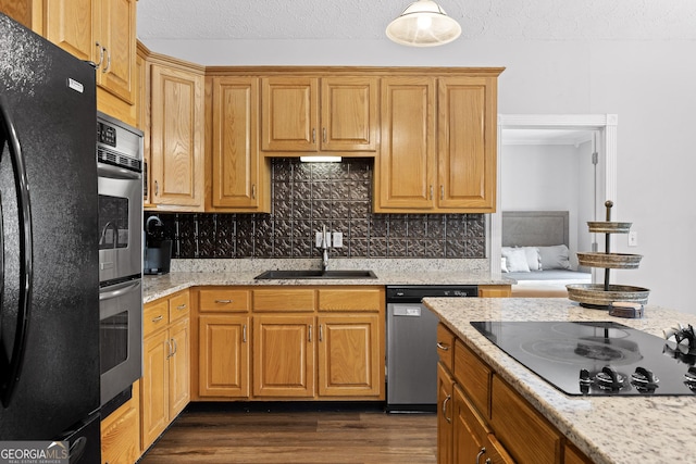 kitchen featuring light stone countertops, sink, tasteful backsplash, dark hardwood / wood-style flooring, and black appliances