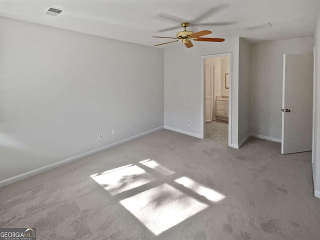 unfurnished bedroom featuring ceiling fan, light colored carpet, and ensuite bathroom