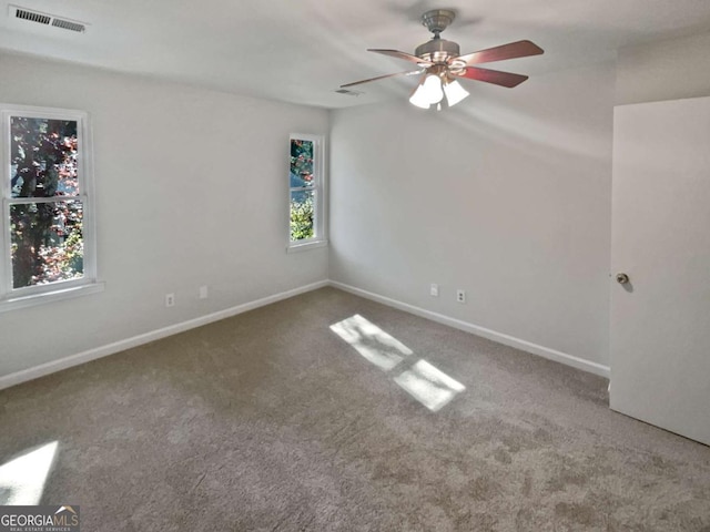 carpeted empty room with ceiling fan and plenty of natural light