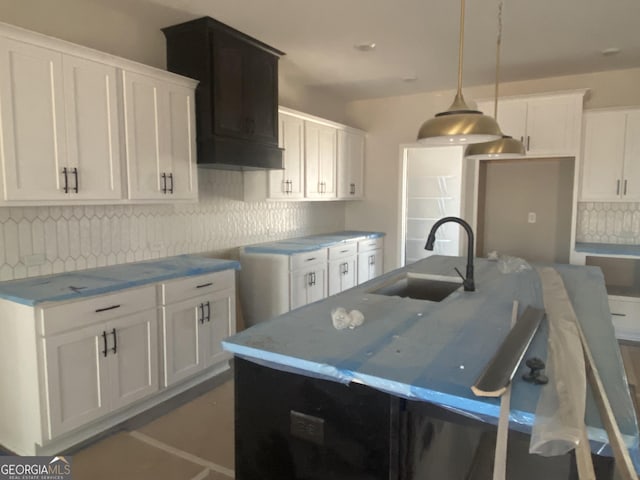 kitchen with white cabinetry, a kitchen island with sink, pendant lighting, and sink