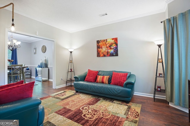 living room featuring dark wood-type flooring, a notable chandelier, and ornamental molding