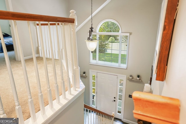 carpeted entryway featuring a towering ceiling