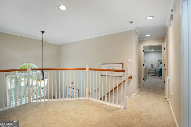 corridor featuring light colored carpet, a textured ceiling, and ornamental molding