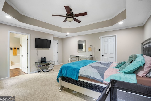 carpeted bedroom with ensuite bathroom, a raised ceiling, ceiling fan, and crown molding