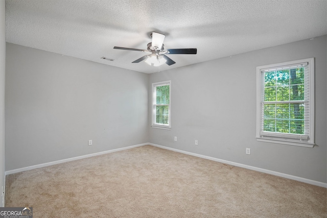 empty room featuring light carpet, a textured ceiling, and ceiling fan