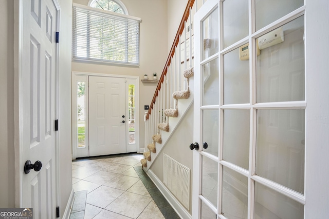 foyer entrance with a towering ceiling and light tile patterned flooring