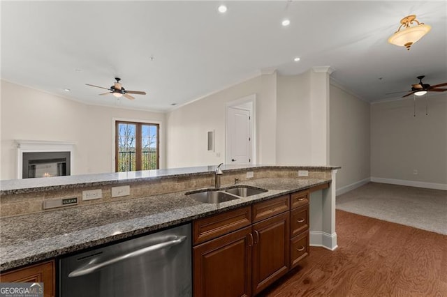 kitchen with stainless steel dishwasher, dark stone counters, sink, and ornamental molding