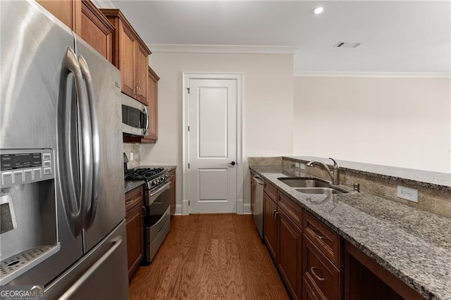 kitchen with sink, stone counters, stainless steel appliances, ornamental molding, and dark hardwood / wood-style flooring