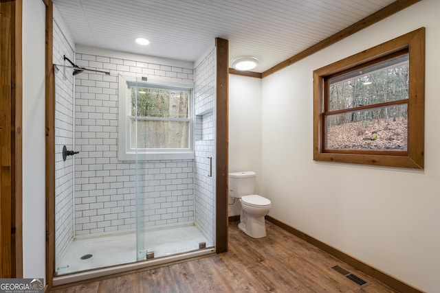 bathroom featuring hardwood / wood-style flooring, toilet, crown molding, and walk in shower