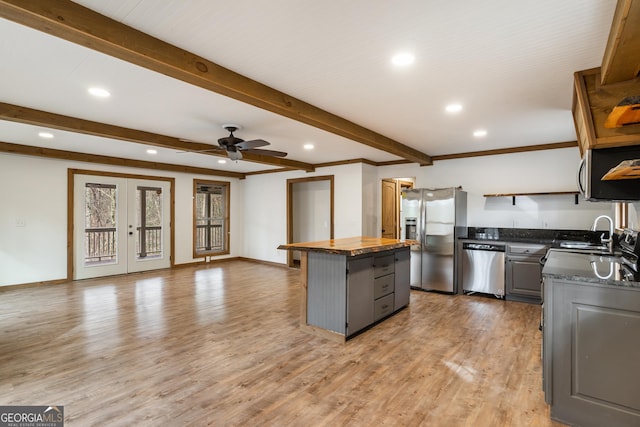 kitchen featuring appliances with stainless steel finishes, ceiling fan, hardwood / wood-style flooring, gray cabinets, and a kitchen island