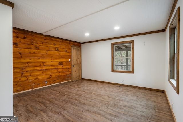 spare room featuring crown molding, hardwood / wood-style floors, and wood walls