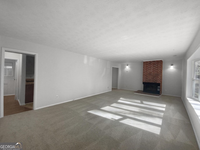 unfurnished living room with light carpet, a fireplace, and a textured ceiling